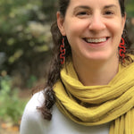 Happy girl wearing large red squiggle earrings in nature by ColorUpLife.