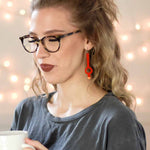 Woman wearing long asymmetrical earrings in burnt red by ColorUpLife.