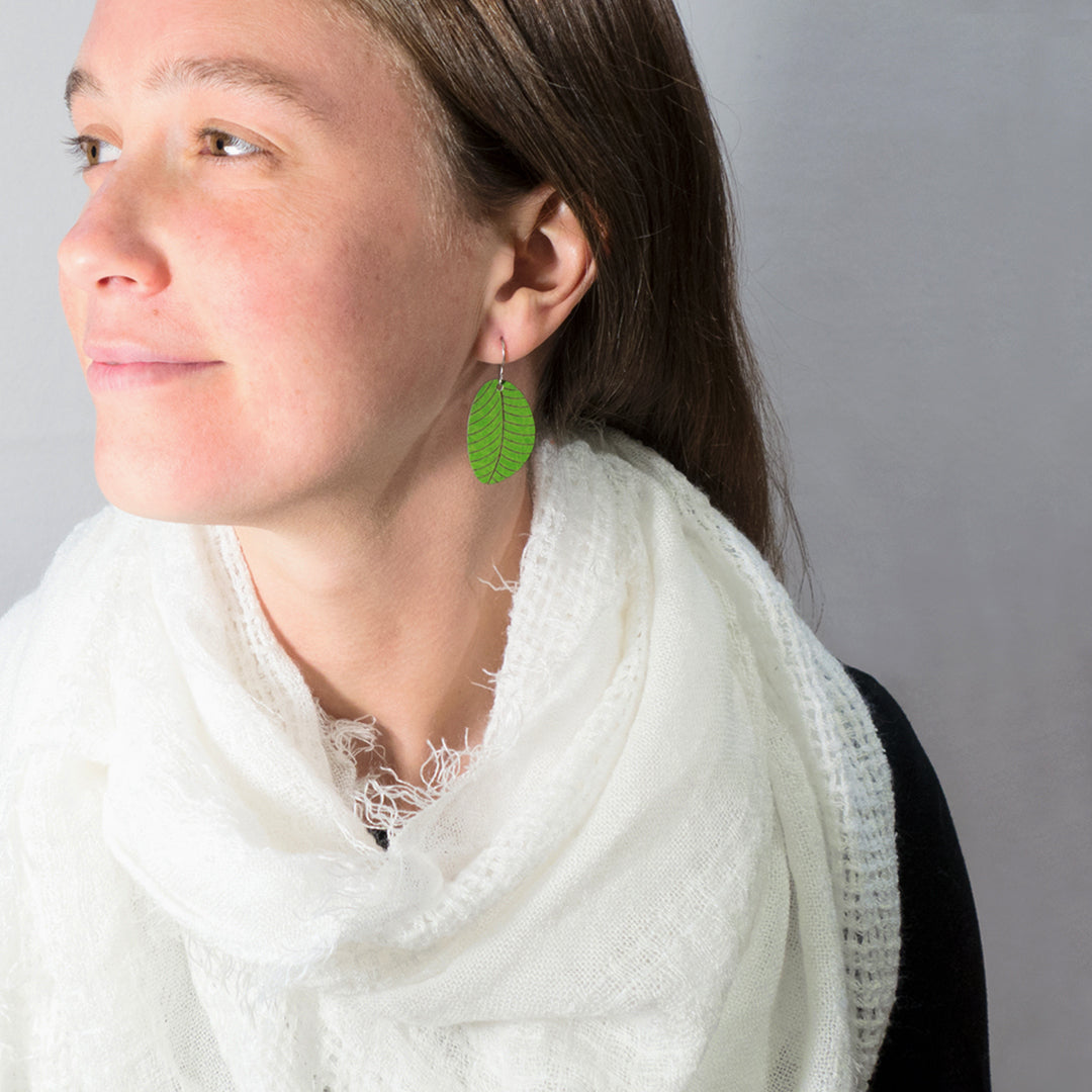 Girl modeling small leaf earrings in sage green by ColorUpLife.