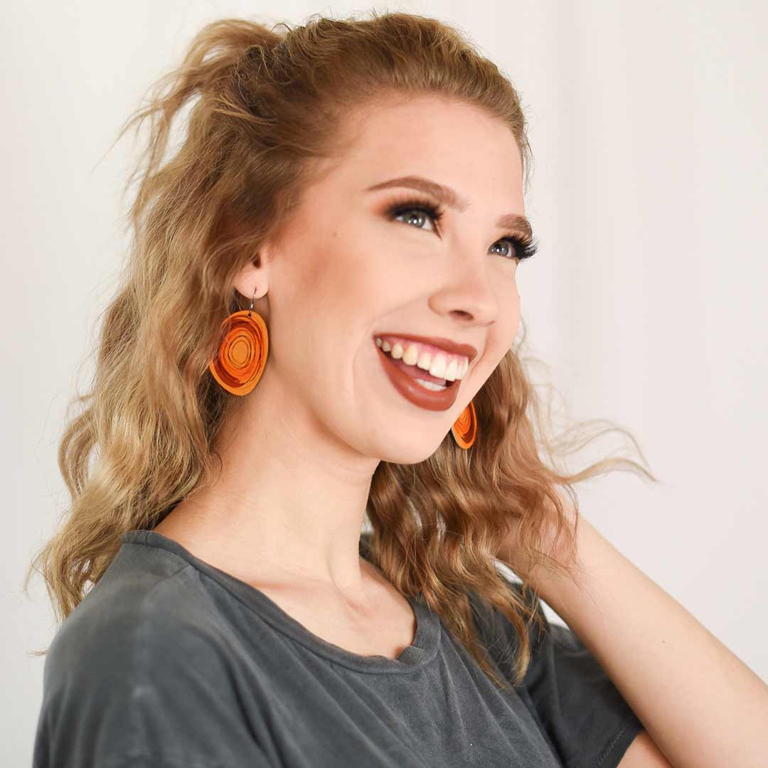 Young adult girl wearing large solid oval-shaped hoop earrings in brown by ColorUpLife.