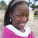 A young girl wears a pair of colorful, abstract floral dangle earrings in rainbow by ColorUpLife